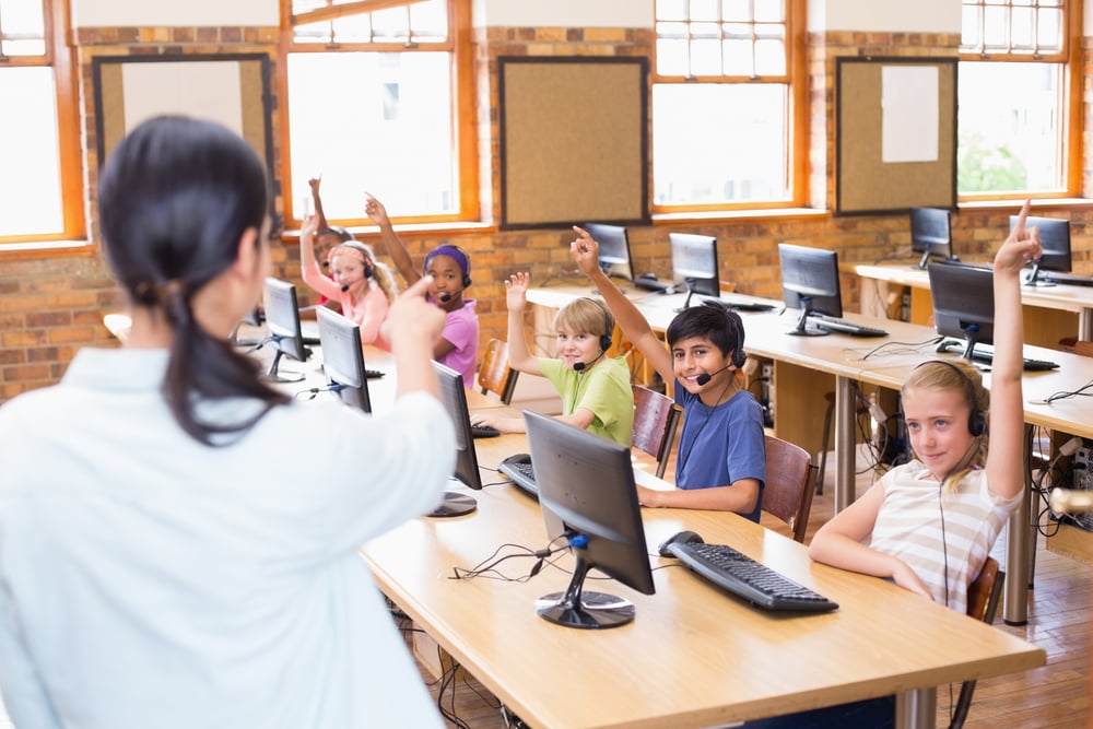 Cute pupils in computer class with teacher at the elementary school