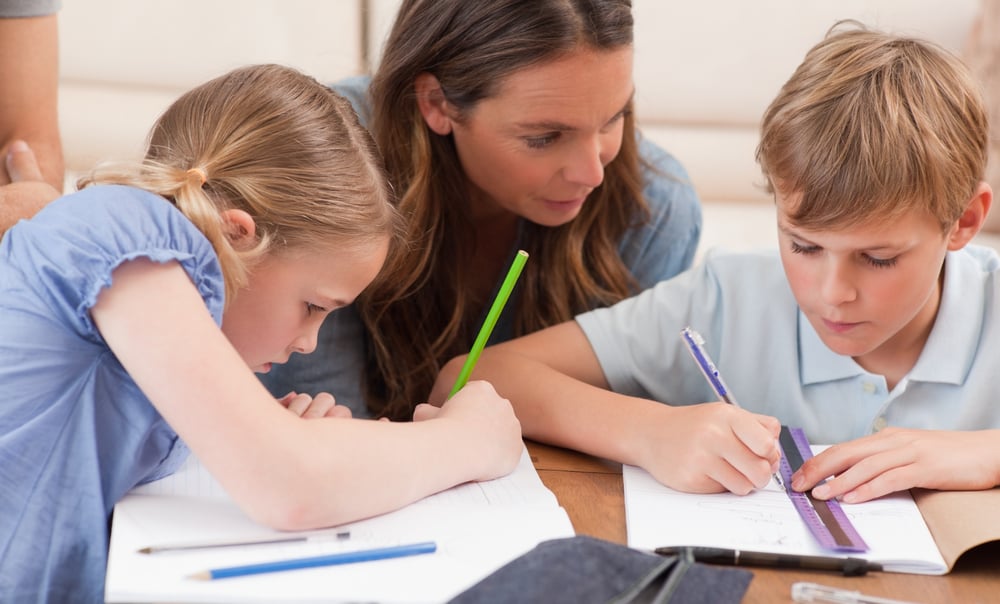 Mother helping her children to do their homework in a living room