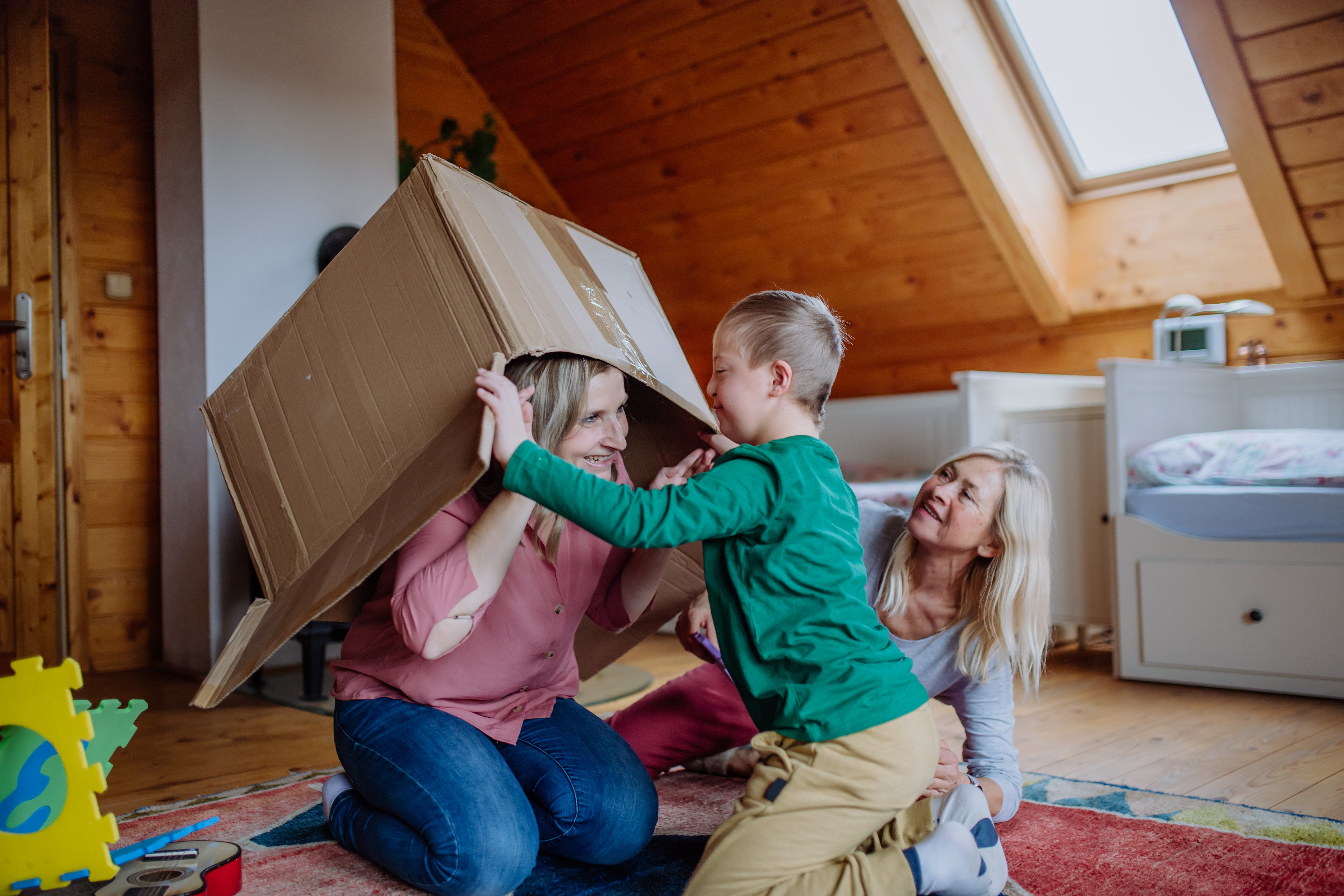 boy-with-down-syndrome-with-his-mother-grandmother-playing-with-box-together-home