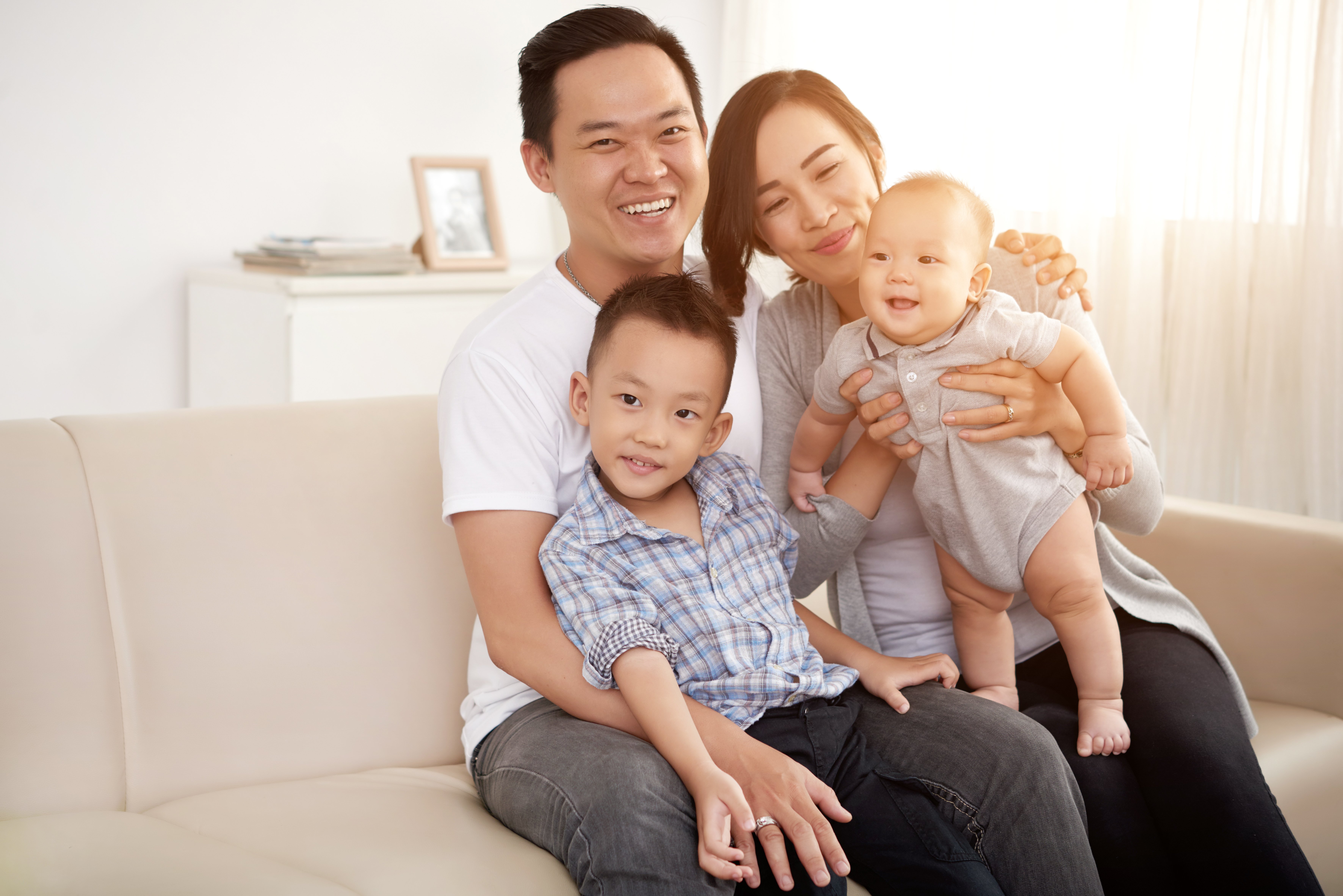 loving-asian-couple-posing-couch-home-with-young-son-baby