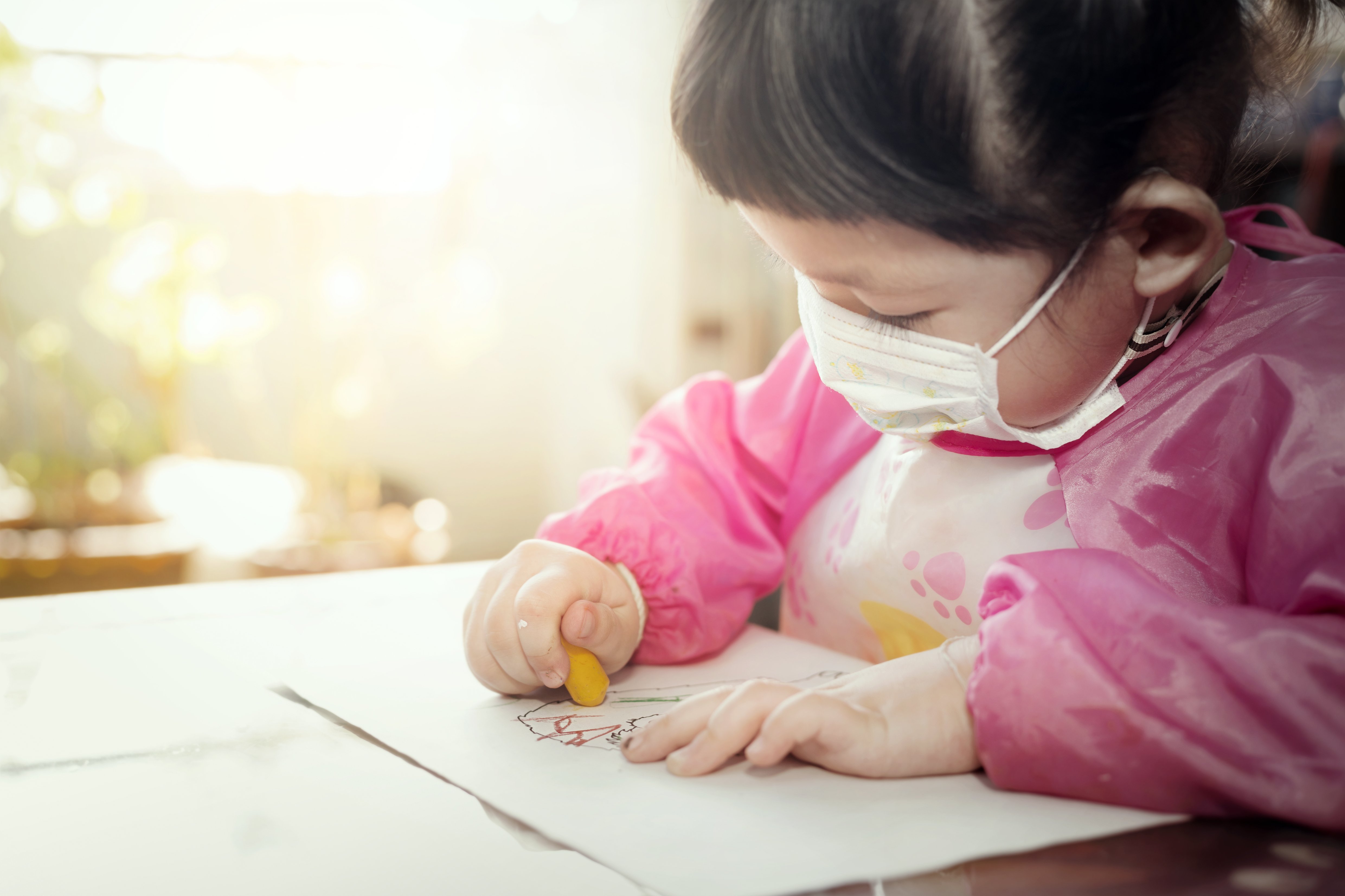 portrait-lovely-asian-girl-wearing-facial-hygienic-mask-drawing-her-art-work-with-crayons-selective-focus-quarantine-home-isolation-during-covid-19-pandemic